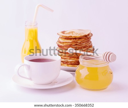 Breakfast - honey and stack of pancakes, tea, orange juice on a plate isolated on white background.  Selective focus.