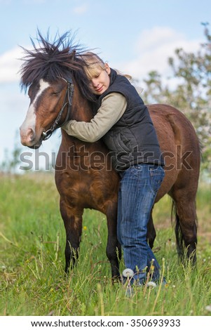 Little girl embracing bay pony.