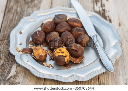 Delicious homemade oven baked chestnuts in a metal plate onwooden table, your perfect winter snack or perfect meal on a Christmas market 