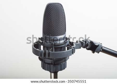 A vocal microphone on a stand isolated against a white background