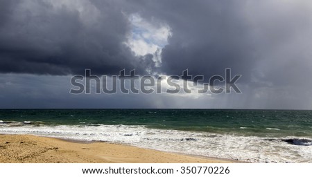 Heavy darkened clouds over  Ocean Beach Bunbury Western Australia on a stormy  late afternoon in autumn with waves breaking  on the wet sandy shore.