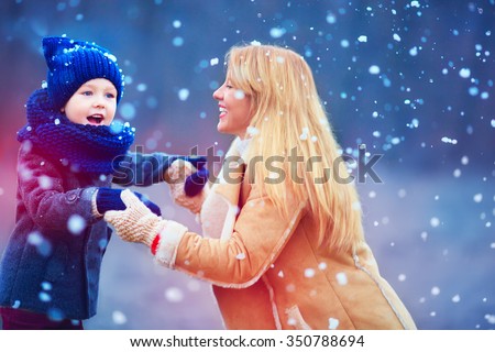 happy mother and son having fun under winter snow