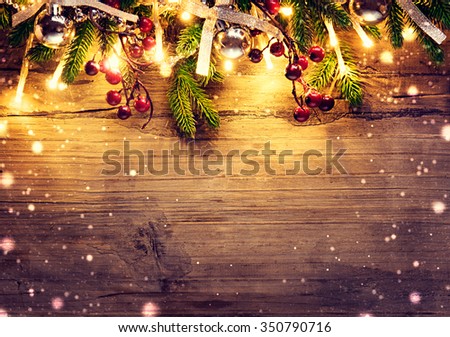 Christmas fir tree with decoration on dark wooden board background. Border art design with Christmas tree, baubles and light garland