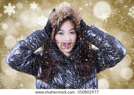 Picture of attractive teenage girl wearing winter jacket with snowflakes and bokeh background