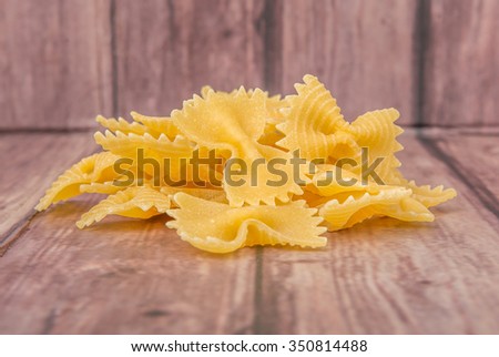 Dried italian bowtie pasta or farfalle over wooden background