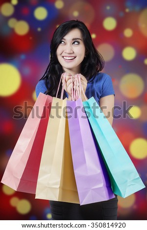 Picture of joyful female shopper holding christmas shopping bags with bokeh background