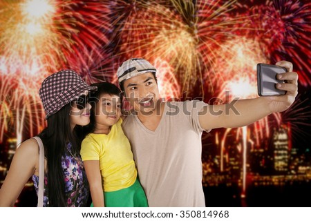 Happy family using mobile phone to take selfie picture in the fireworks festival at the new year celebration