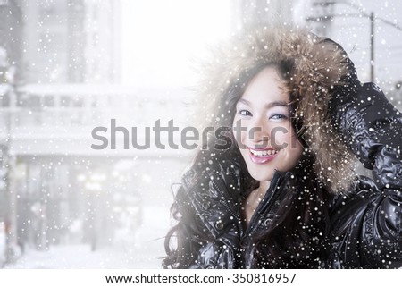 Picture of a lovely teenage girl wearing winter clothes with furry hood on a snowy day
