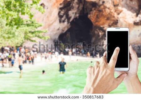 Man use smart phone, blur image of the beach in Krabi Thailand as background.