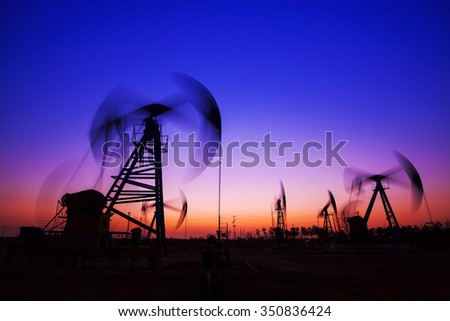 Oil field scene, the evening of beam pumping unit in silhouette 