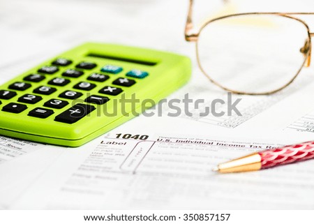 Business work station with paperwork income tax return, calculator and pen and dollar