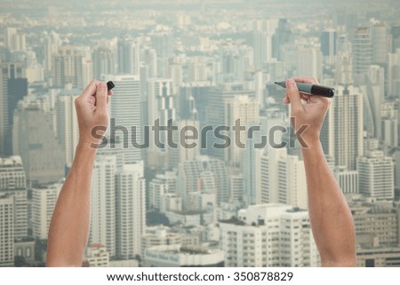 Man hands holding marker pen with skyline background