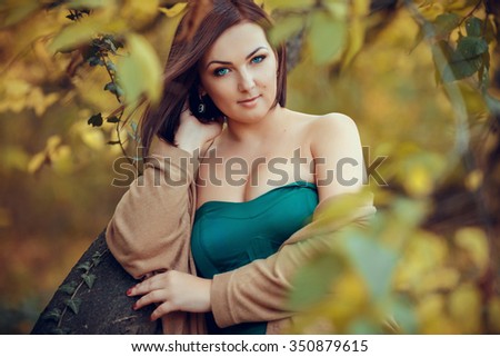 portrait of a beautiful young woman in a autumn park. pictures in warm colors. Model plus