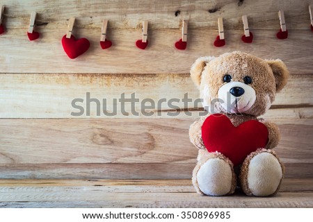 Teddy bear holding a heart-shaped pillow with plank wood board background Royalty-Free Stock Photo #350896985