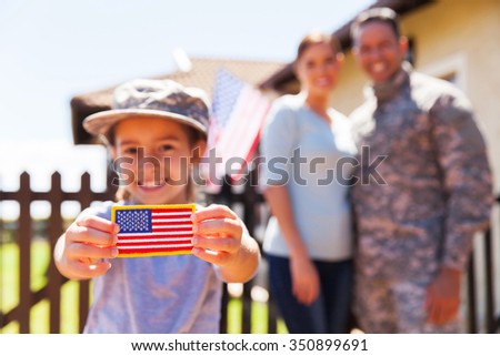 little girl holding american flag badge in front of parents