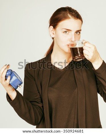 young beauty woman in business style costume waking up for work early morning on white background with clock drinking coffee tired face