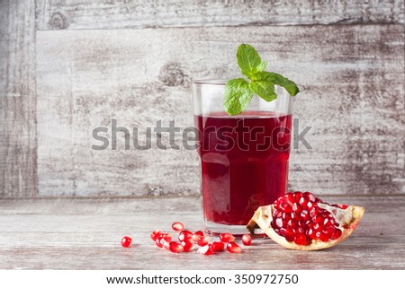 A glass of pomegranate juice with fresh pomegranate fruits on wooden table