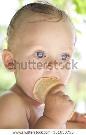 Joyful cool child girl eating ice cream outdoors near the swimming pool. Happy toddler girl with blond hair and deep blue eyes eating tasty cold sweet on a hot summer day. Portrait. Colorful photo.