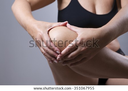 Woman with pain in the knee on a gray background