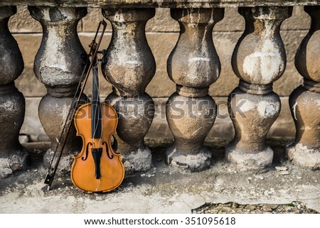 violin on old retro fence background in perspective Beautiful music instrument standing near cracked wall backdrop Copy space for inscription