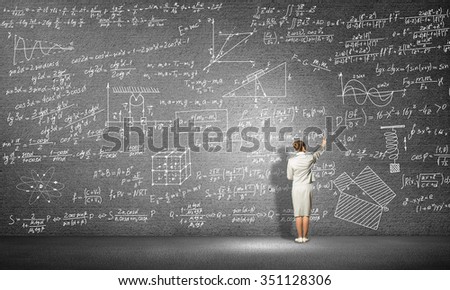 Rear view of woman drawing formulas on blackboard with chalk