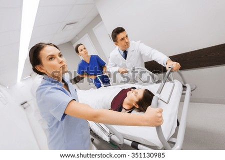 profession, people, health care, reanimation and medicine concept - group of medics or doctors carrying woman patient on hospital gurney to emergency Royalty-Free Stock Photo #351130985