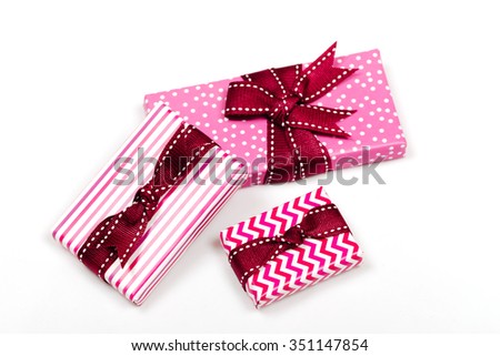 Pink and striped boxes with gifts tied bows on white background