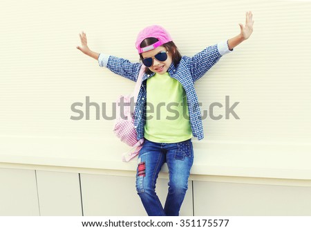 Fashion little girl child wearing a sunglasses and baseball cap in city over white background