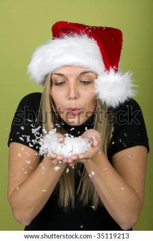Woman in Santa hat blowing snowflakes from hands