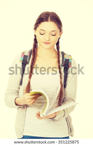 Studying thoughtful teen woman reading her notebook.