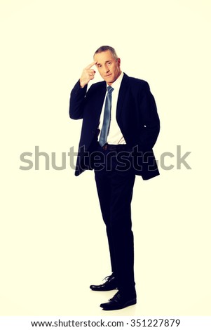 Full length businessman gesturing with finger against temple