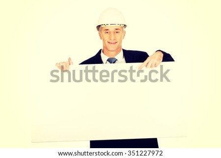 Mature engineer with hard hat holding empty banner.