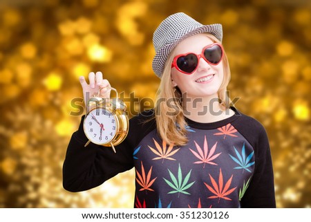 Pretty girl holding alarm clock on golden bokeh digital background