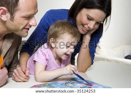 Couple helping their young daughter with an activity book