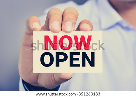 NOW OPEN, message on the card shown by a man Royalty-Free Stock Photo #351263183