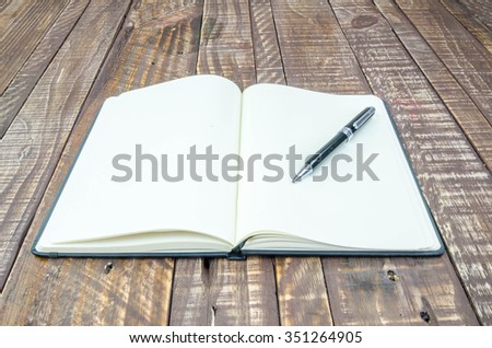 Notebook and pen on wood background .