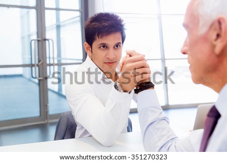 Two businessmen competing arm wrestling in office