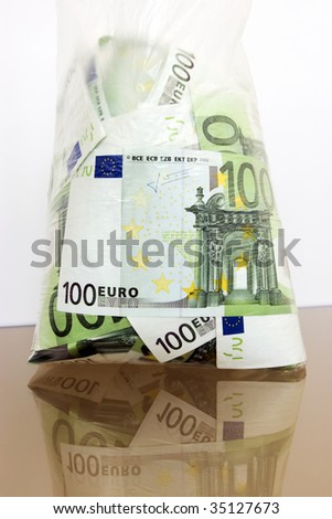 Many hundred denominations of euro in a cellophane package on a reflecting surface