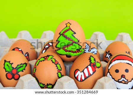 Christmas egg with faces drawn arranged in carton on green background