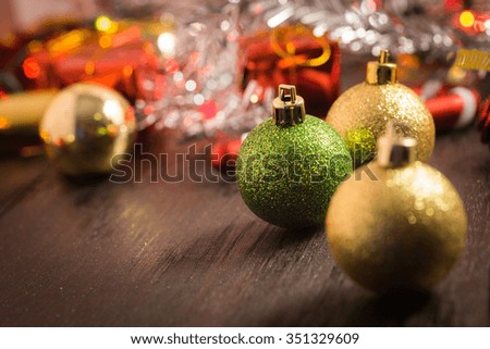 selective focus Christmas background with a red ornament, golden gift box, berries on black wood blackground still life