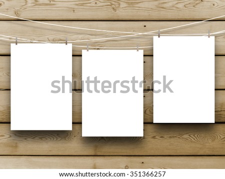 Three paper sheet frames hung by pegs on brown wooden boards background