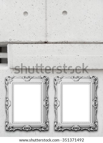 Two grey baroque picture frames on grey modern concrete wall background
