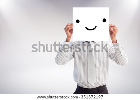 Businessman holding a white card covering his face against grey background