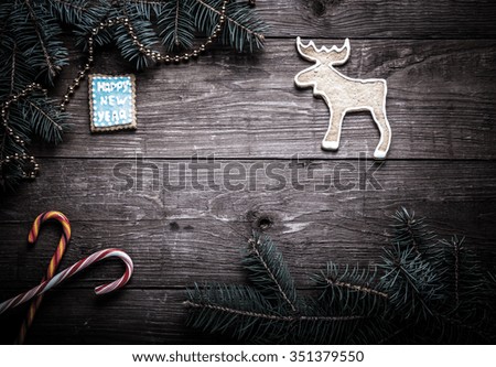 Gingerbread homemade cookies with icing and christmas tree branch on a wooden table or board for background. New year theme. Toned.