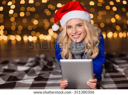 Portrait of a smiling woman lying on the floor with tablet computer over holidays lights background