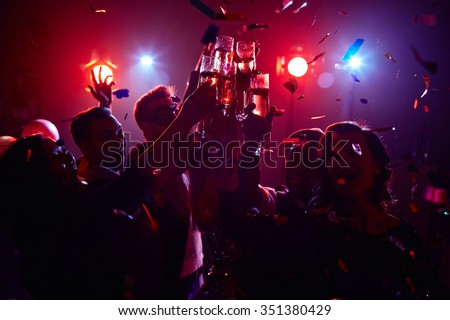 Young friendly people toasting in night club Royalty-Free Stock Photo #351380429