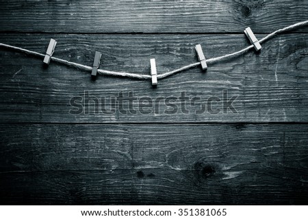 Colored clothespins on rope on a wooden table or board for background. Space for text. Toned.