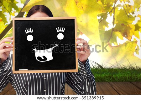 Businesswoman showing board against wooden floor against leaves