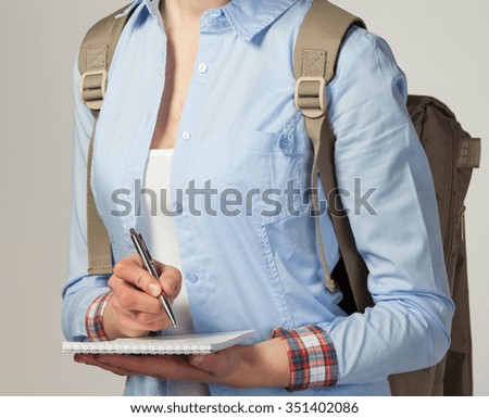 Girl holding dairy and writing something;  grey background