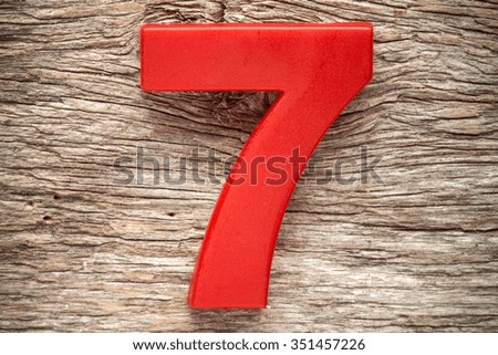 Red number seven on the wooden background